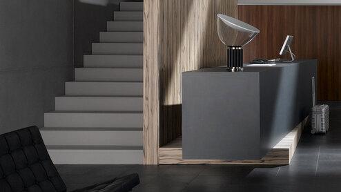 Hotelappartment Untergeschoss mit Holzmobiliar, dunklem Parkett und Treppenaufstieg