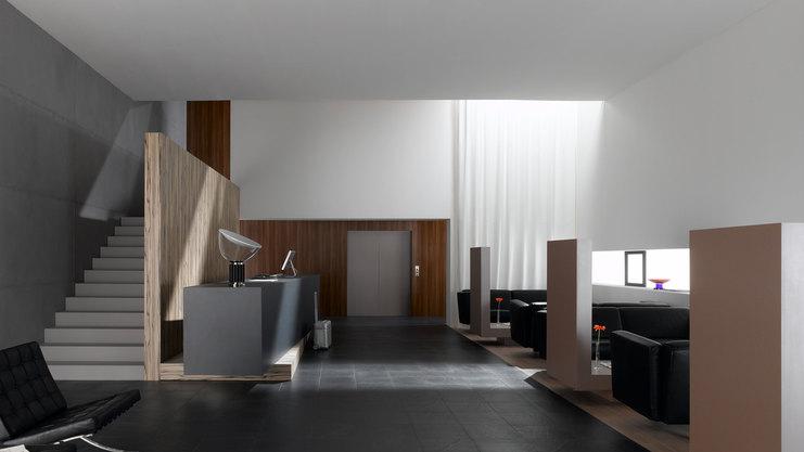 Hotelappartment Untergeschoss mit Holzmobiliar, dunklem Parkett und Treppenaufstieg